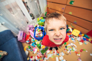 Defiant young boy in messy bedroom