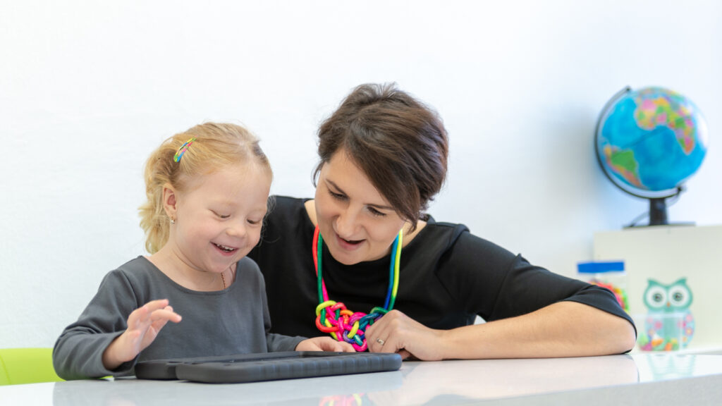 A female applied behavior therapist and an autistic girl use an AI tool to observe behavior, collect data, and improve analysis strategies.