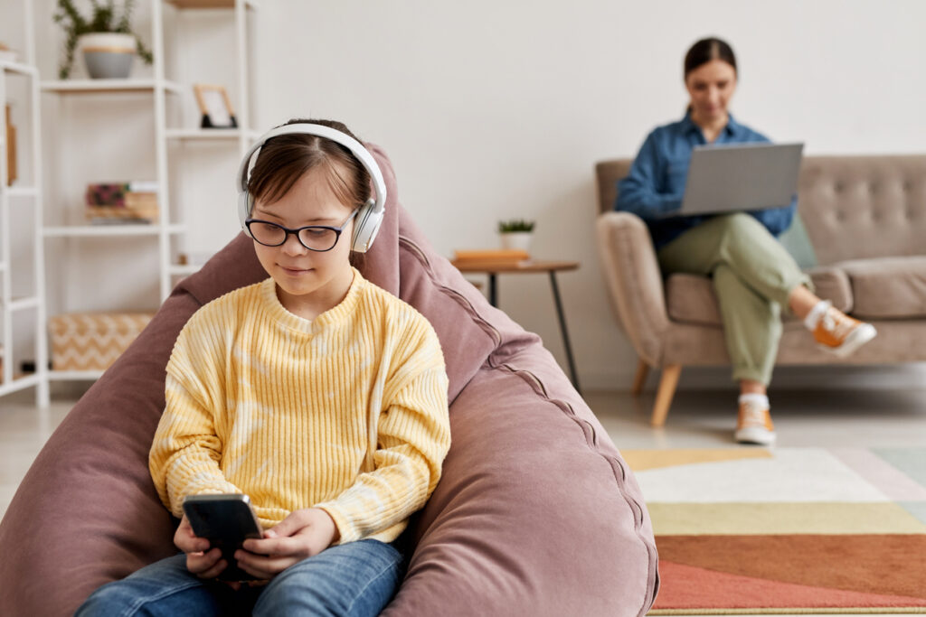 Girl with autism using AI tools on her phone while applied behavior analysis therapist supervises in the background.